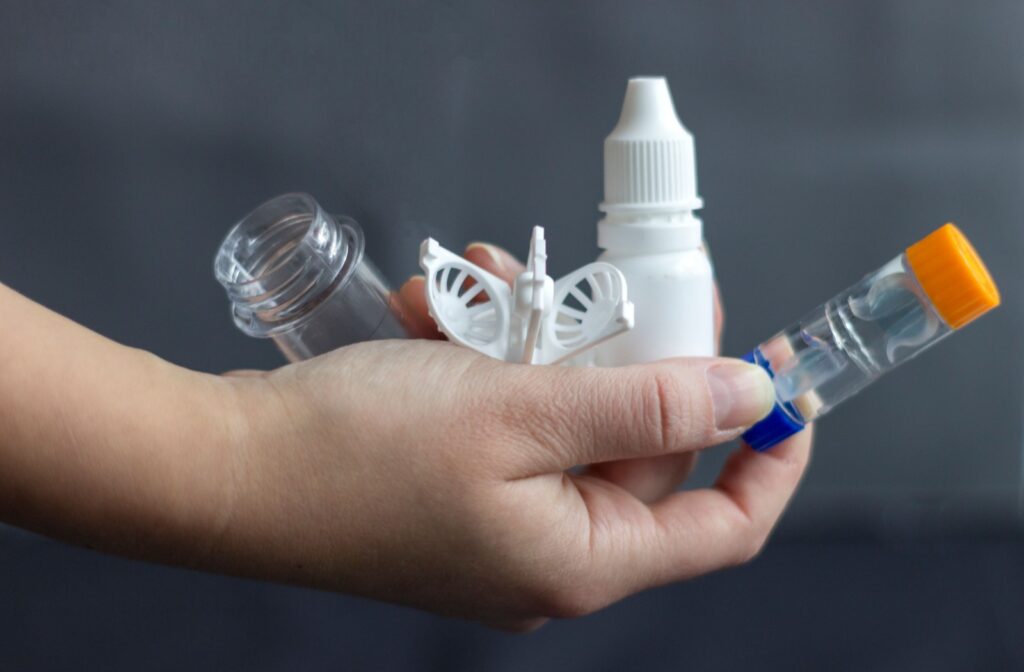 A person holding several tools used for myopia control, including ortho-k lenses and eye drops.